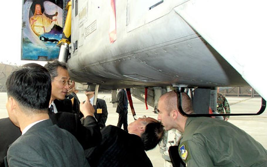 1st Lt. Jeff Burley, right, an A-10 pilot with the wing’s 25th Fighter Squadron answers questions about the aircraft for the visiting South Korean journalists and professors.