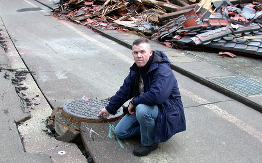 Maj. Paul Melchior, from Iwakuni Marine Corps Air Station&#39;s Marine Aviation Logistics Squadron 12, is shown earlier this month on a typical street in the Niigata earthquake zone, in front of a family&#39;s two-story home that collapsed in the Oct. 23 temblor.