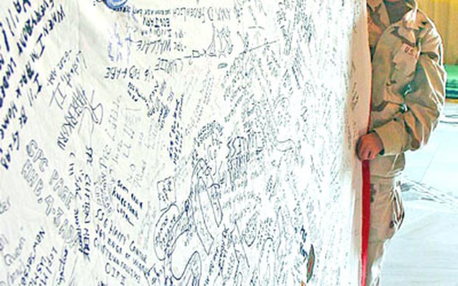 Sgt. Nicole Smith of the 121st Signal Battalion, 1st Infantry Division, holds the quilt she created during her off-time in Iraq that commemorates those who worked there. One side of the quilt has more than 100 panels; this side is signed by hundreds of soldiers who have been stationed in Iraq. The quit was sold on eBay for $9,500, and the money will go to a 1st ID charity.