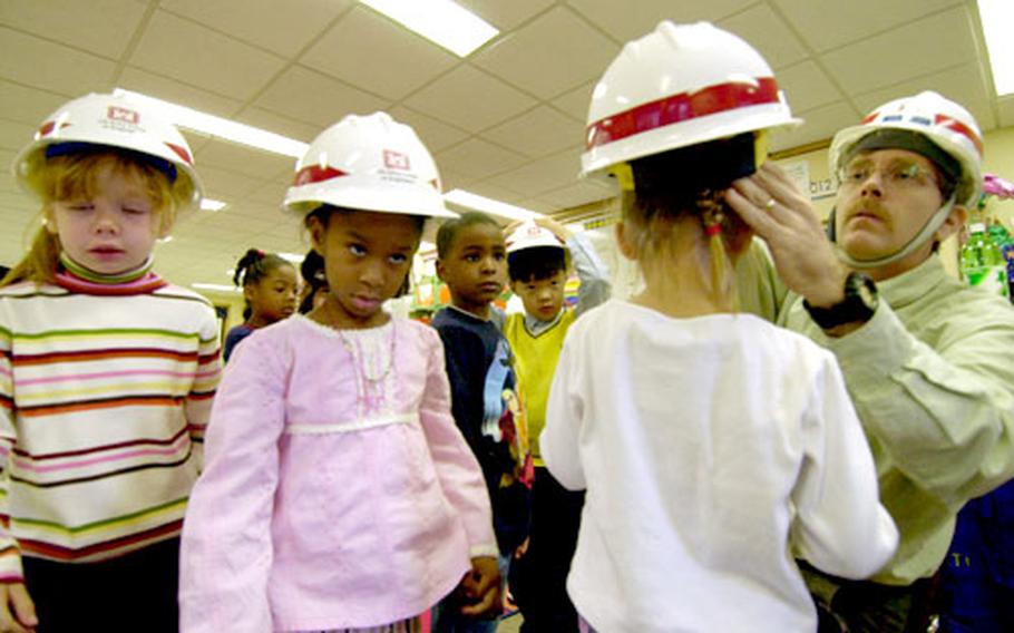 Don Schlack, chief of the Far East District&#39;s environmental section, hands out hard hats before he and a group of Yongsan Garrison kindergartners head out to watch a drilling team.