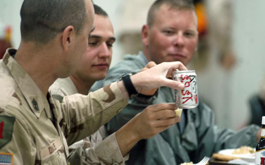 Three soldiers from the 369th Transportation Company — from left, 1st Sgt. David Dibble, Spc. David Kingsland and Staff Sgt. Ken Colson — toast the holiday Thursday at a dining facility at Logistics Support Area Anaconda.
