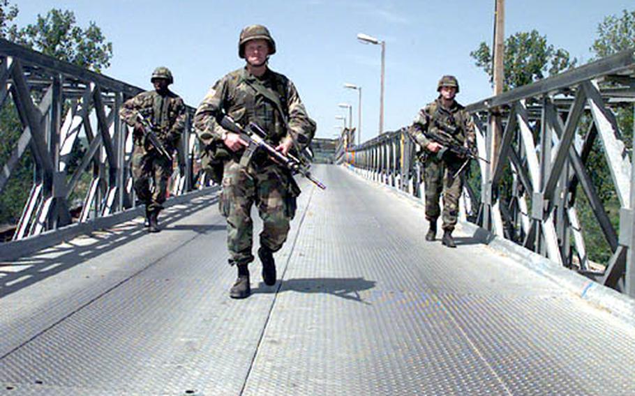 Spc. Dexter Akers, Sgt. Beau Pendergraft and Spc. Wayne Outler, all of Alpha Team, 3rd Squardon, 1st Platoon, Bravo Company, 2 Battalion, 14th Infantry Regiment out of Fort Drum, N.Y., cross the bridge over the Sava river connecting Slavonski Brod, Croatia, with Bosanski Brod, Bosnia, in May, 1997.