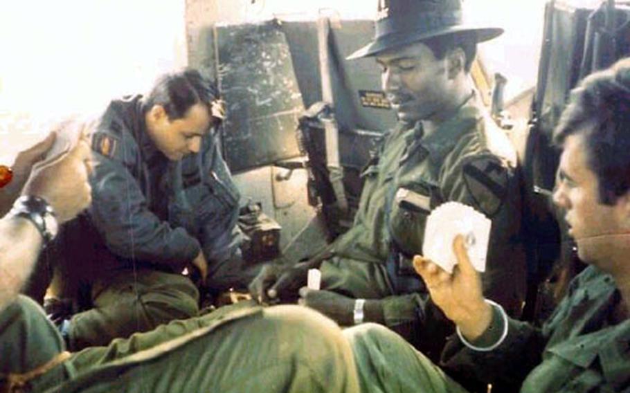Chief Warrant Officer 5 Robert "Bobby" McNeal, with hat, plays poker with fellow pilots during down time in Vietnam in the early 1970s.