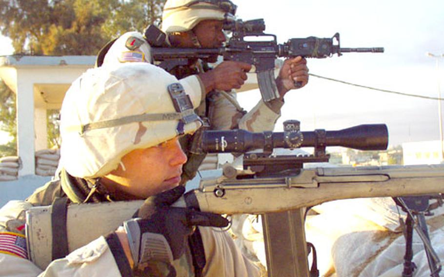 Spc. Greg McMeekan, 23, front, and Sgt. Melvin Davis, 32, scan the Bayji skyline from the roof of the mayor&#39;s office. The main street has been closed to Iraqi traffic during the day for the past several weeks during a violent uprising in the city so that U.S. supply convoys can safely pass. McMeekan and Davis are members of Company A of the 1st Battalion, 26th Infantry Regiment from Schweinfurt, Germany, but are currently attached to Task Force 1-7.
