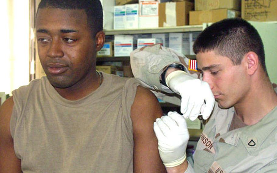 Pfc. Barnaby Johnson, 23, a medic at Forward Operating Base Wilson near Ad Dawr, Iraq, gives a flu shot to Spc. Claude Weathers, 22, of the 1st Squadron, 4th Cavalry Regiment.