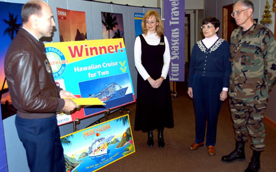 Brig. Gen. Bill Rew, left, 35th Fighter Wing and Misawa Air Base commander, presents Maj. Wendell Brenneman, right, and his wife, Deb, second from right, with their Hawaiian cruise prize packet Wednesday morning. Brenneman was one of three top grand prize winners in the PACAF Pentathlon online board game contest.