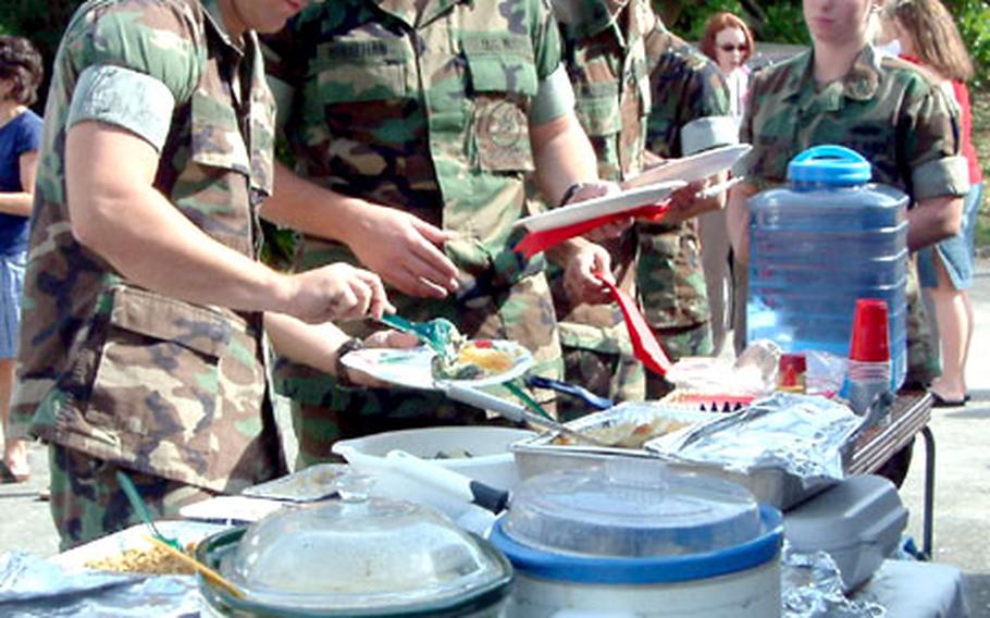 Seaman John Bough, left, Seaman Apprentice Tim Whelehan, next to Bough, and other Seabees load their plates at a picnic held Tuesday in their honor for work done renovating two World War II-era Quonset huts for the Navy Gift Shops on Camp Lester, Okinawa.