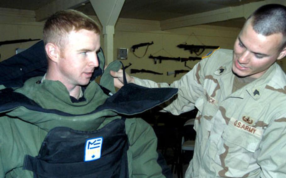 Sgt. Corey Wybourn of the 29th Signal Battalion tries on a bomb suit with the help of Sgt. Daniel Brunick of the 716th Ordnance Company (EOD). The EOD unit held an open house Saturday at LSA Anaconda, Iraq, for anyone interested in becoming an EOD specialist. About 30 soldiers, including Wybourn, attended.