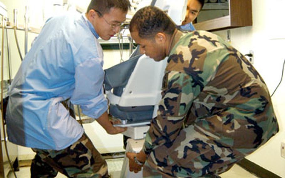 At the Camp Walker dental clinic in Taegu, soldiers haul away a dental chair as they ready the clinic for a year-long, stem-to-stern renovation. From left are Sgt. Park Sung-min, Cpl. Conrad Rath and Pfc. Jang Eun-soo, all of the 618th Medical Company.