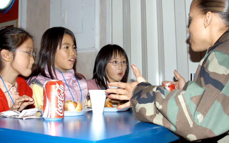 Staff Sgt. Alexsandra Fajardo, right, of Puerto Rico talks Wednesday with students from Seoul's Moon Jeong Elementary School at the USO at Camp Kim, South Korea. The students visited Camp Kim to meet U.S. soldiers and practice English. The field trip was part of USFK's Good Neighbor Program.