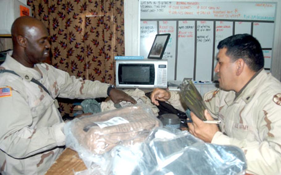 Sgt. 1st Class Ronnie Haith, left, of 13th Corp Support Command Headquarters Company turns in his nuclear, biological and chemical gear to Spc. Fernando Hernandez at LSA Anaconda, Iraq, in preparation for a trip home after nearly one year at the base.