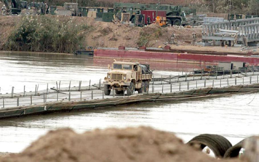 At a bridge floating on the Tigris River in Iraq, convoys often face long waits because only one truck can cross at a time. During one recent mission, members of the 369th Transportation Company had to wait nervously for four hours as other convoys made their way across the bridge. A new bridge is being built by Marines that will be able to handle more traffic.