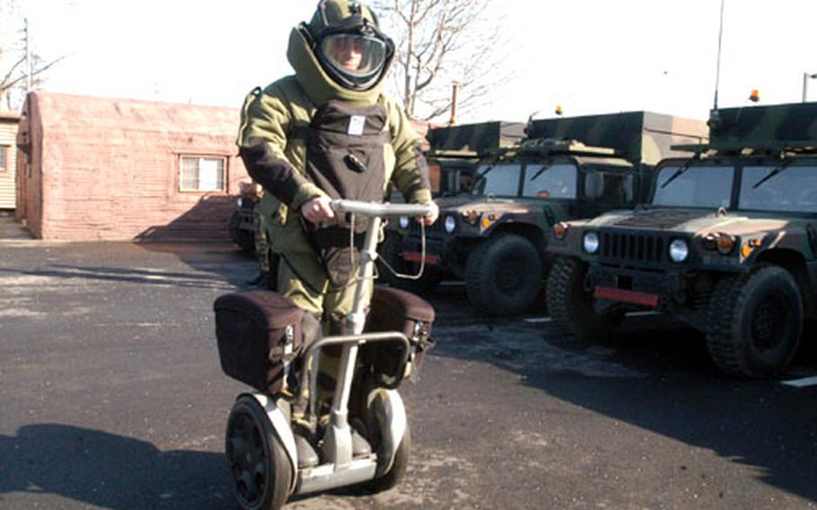 Staff Sgt. Robert Wells rides the Segway while wearing his bomb disposal suit at Camp Red Cloud.