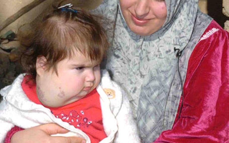 Baday Amir Abdel-Jabar holds her daughter, Fatemah, at their home in Mandali, Iraq.