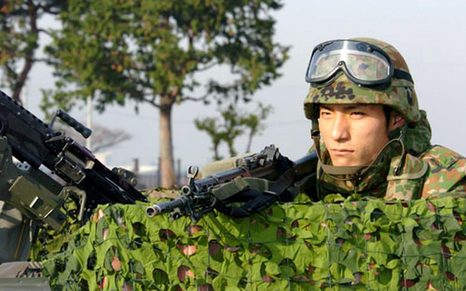 A soldier from the Japanese Ground Self-Defense Force mans his machine gun during the joint Guard and Protect exercise Tuesday with airmen at Yokota Air Base. The exercise was to simulate protecting the installation from an enemy attack.