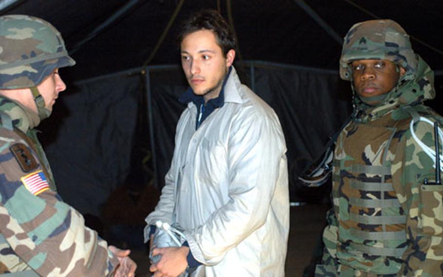 Staff Sgt. Scott Adkins, left, a 92nd Military Police Company medic, talks to a “detainee” Thursday who claims he was maltreated during his capture. The role-playing detainee was being escorted through detention facility processing by Sgt. Tyion Stanley, right. The three were training at the Combat Maneuver Training Center in Hohenfels, Germany, to gear up for an Afghanistan deployment next spring.