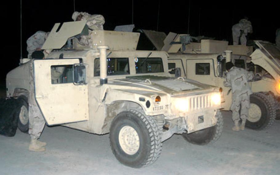 Combat airmen at Balad Air Base, Iraq, work in the pre-dawn hours to prepare their armored Humvees for duty as security for a convoy from the base. Combat airmen have been trained for the job of convoy security to help supplement Army security troops.