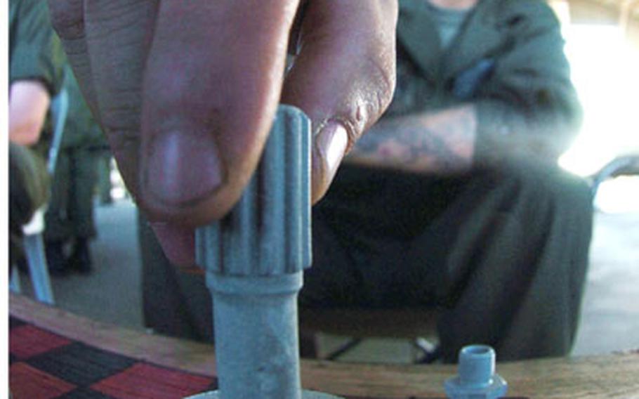 Cpl. Daniel Shannon from Marine Medium Helicopter Squadron 262 moves his chess piece during a break. The chess set was improvised from small worn aircraft parts.