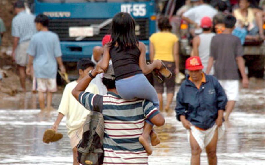 A man carries his daughter Tuesday as he walks through flooded streets of Infanta, one of the drop-off points for U.S. Marines delivering relief supplies in the Philippines.