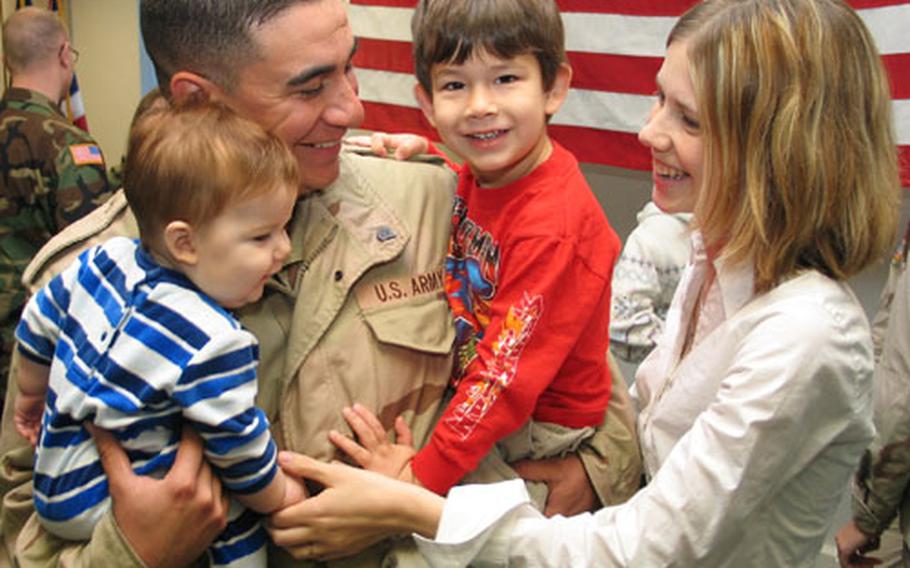 Spc. Damien Demasio reunites with his wife, Amber, and children Jaren, 6 months, and Christian, 3, on Wednesday at Warner Barracks in Bamberg, Germany. Nine soldiers from Headquarters, Headquarters Battery, Division Artillery, 1st Infantry Division returned to Bamberg from Iraq to open up the 1st Battalion, 6th Field Artillery dining facility in preparation for the division’s return in February.