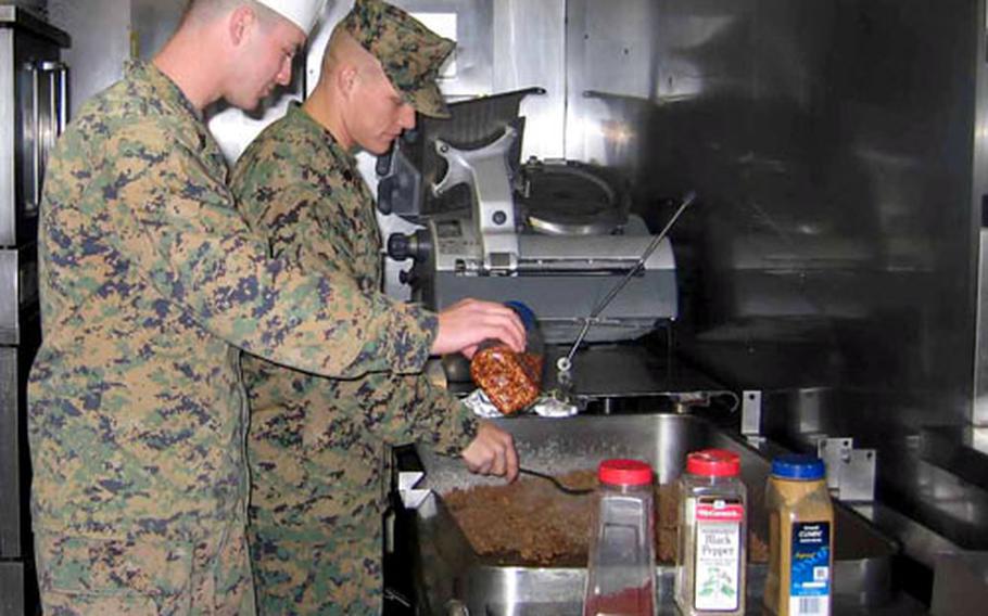 Cpl. Dave Tullos, right, with Sgt. Joseph Kast, Camp Mu Juk’s galley captain, tend the grill Thursday in the galley at the remote camp near Pohang, South Korea. The Marines are laying on a big holiday dinner and party Dec. 23 to be followed by a four-day weekend for the Marines and Navy Seabees stationed there.