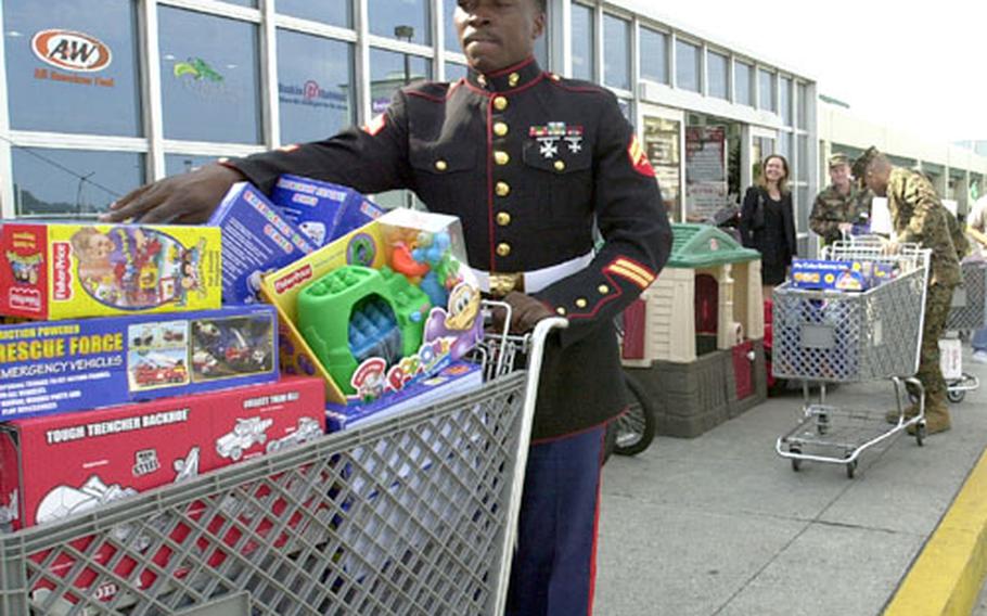 Cpl. Andrew O. Vanhorne, Toys for Tots coordinator, pushes one of many shopping carts full of toys purchased by members of Commander Fleet Activities Okinawa to a 60-passenger Green Line bus on Friday.