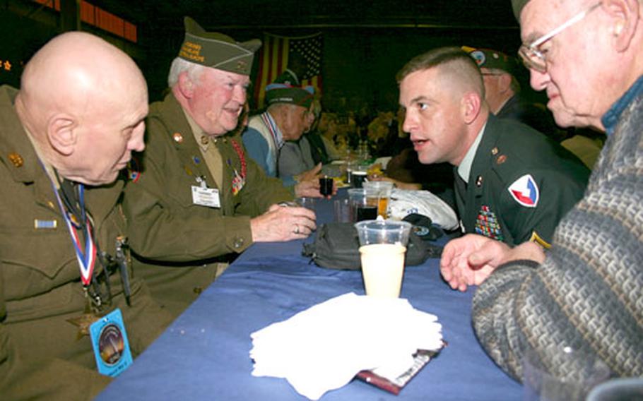 Sgt. 1st Class Jon A. Cox chats with some of the more than 150 World War II veterans who attended a USO night hosted by the U.S. Army Field Support Battalion in Dudelange, Luxembourg, on Thursday. The event, held in an area converted into a 1940s-era canteen complete with Hershey bars and an Andrews Sisters-style trio, was part of the observance of the 60th anniversary of the Battle of the Bulge. Cox is assigned to the Field Support Brigade-Europe.