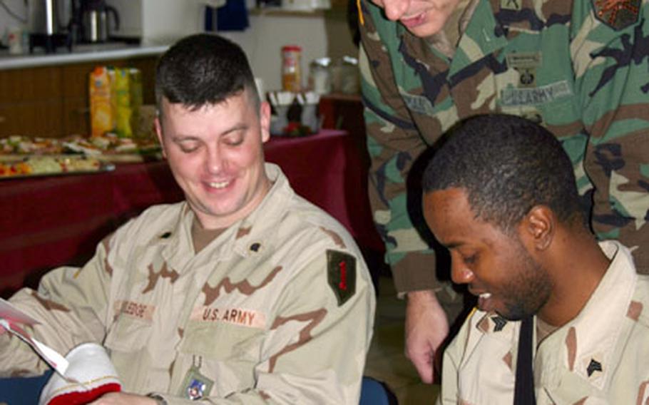 Lt. Col. Jeffrey Feldman, commander of the 280th BSB based in Schweinfurt, leans over to talk to Spc. Michael Rutledge, left, and Sgt. Keyonta Oates, both of the 299th FSB, as the soldiers look through the gift bags given to them at Friday’s Christmas party.