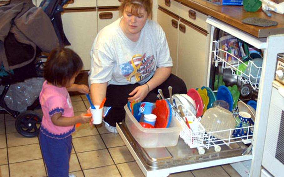 Wilmarie Ortiz, 16 months, helps Allison Tucker unload the dishwasher Friday at Tucker’s home in Bamberg, Germany. Tucker is a family child-care provider on Warner Barracks, and cares for seven children in her home.