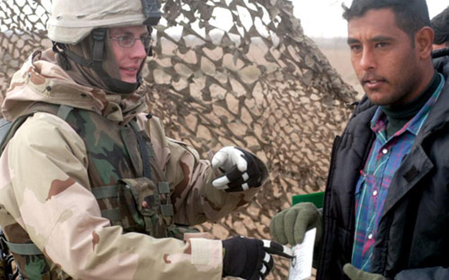 Sgt. Justin Jones of Company D, 181st Support Battalion, 81st Brigade Combat Team checks an Iraqi worker.