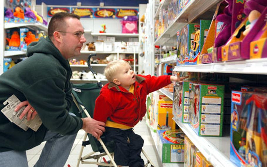 John Crowe, of Rhein-Main Air Base, Germany, looks over the shelves of toys with 21-month-old son John Crowe Jr. at the Toyland at Mainz-Kastel Storage Station in Germany.