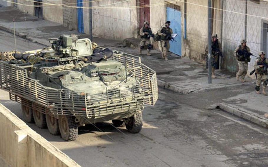 Soldiers of Alpha Company, 1st Battalion, 24th Infantry Regiment, 1st Brigade, 25th Infantry Division Stryker Brigade Combat Team run past a Stryker vehicle during Operation Indy in Mosul, Iraq, on Nov. 11.