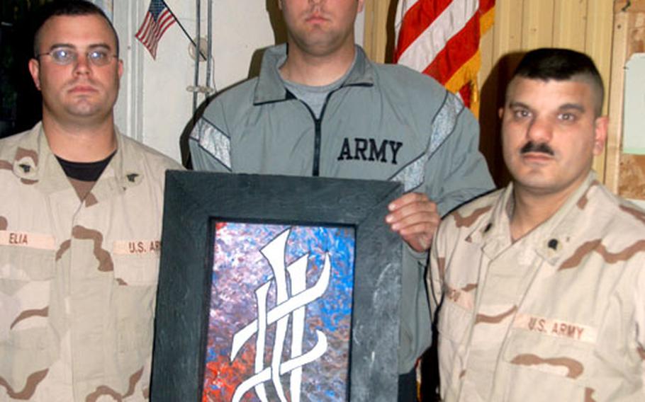Sgt. Rocco Elia, Sgt. Joe Bolland, and Spc. Chris Antoniou, left to right, pose with a painting done by Sgt. Aaron Anslow to honor a fellow 660th Transportation Company soldier killed while on duty in Iraq.