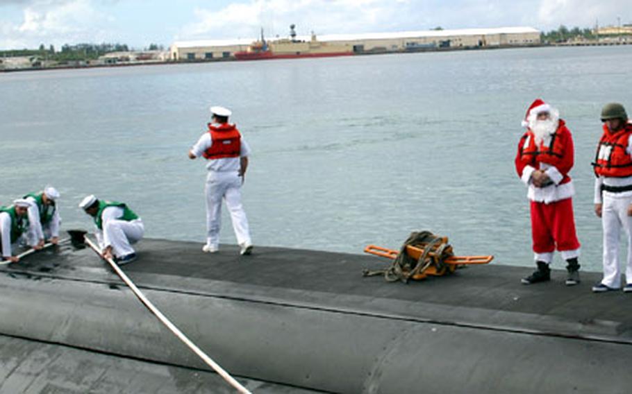 Santa — wearing a regulation life vest, of course — stands topside as the USS Houston pulls into its new permanent base on Guam.