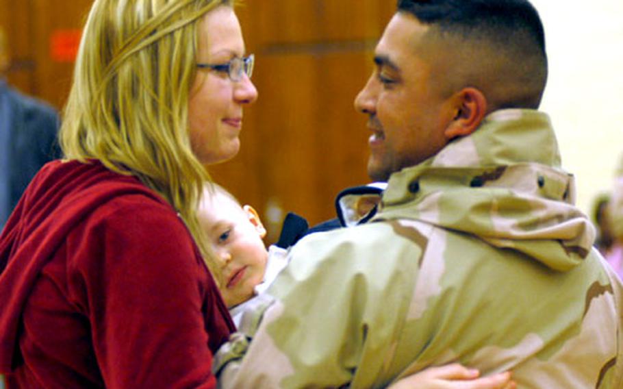 Sgt. Jose Sapien, of the 574th Supply and Services Company, greets his wife, Martina, and son, Damian, at the Mannheim military community sports area Tuesday night after a year of deployment in Iraq.