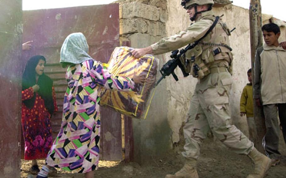 2nd Lt. Dan Hover, of Company A, 1st Battalion, 69th Infantry Regiment, gives a blanket to a family in Hora al Bosh, Iraq.