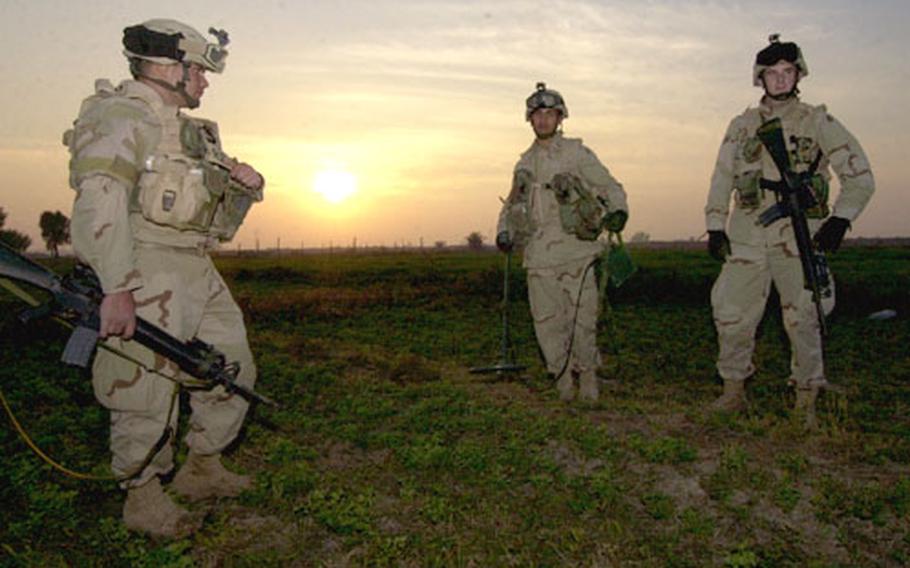 Members of the 1st Platoon, Company A, 1st Battalion, 69th Infantry Regiment, sweep a field where they suspect a weapons cache might be buried.