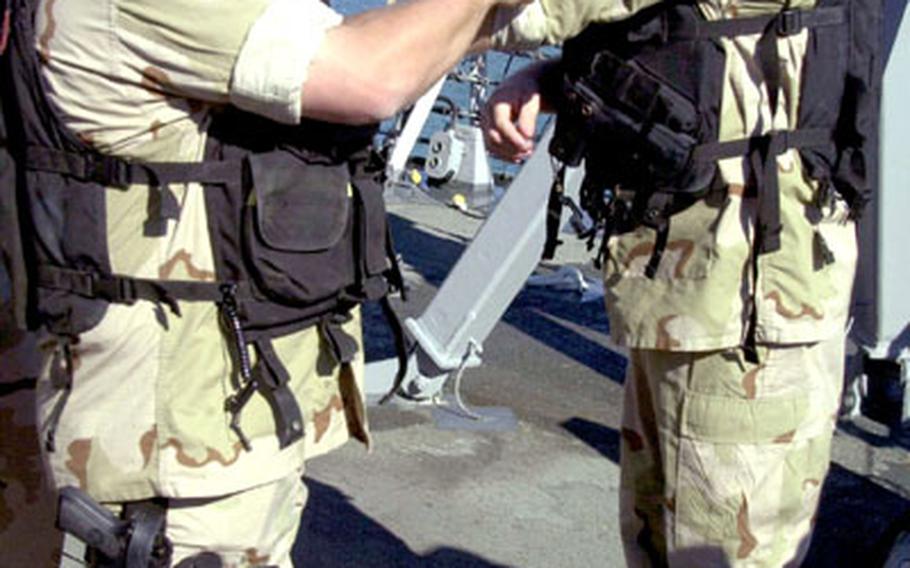 Petty Officer 3rd Class Mark Fore, left, helps Lt. j.g. Joshua Wolf adjust his uniform aboard the USS The Sullivans Tuesday at Naval Station Rota, Spain. Both are members of the destroyer's boarding team.