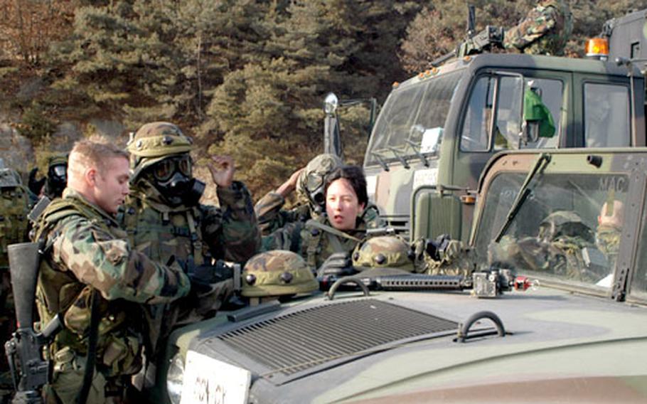 Soldiers from 2nd Infantry Division’s Aviation Brigade remove nuclear, biological, chemical protective gear during convoy training at Rodriguez Range. The convoys included a mix of Humvees, light medium tactical vehicles and a gun truck carrying a mounted .50-caliber machine gun.