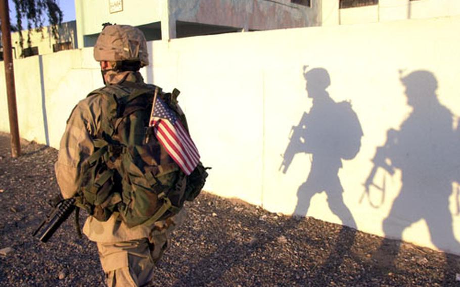 Spc. Javier Aguilar and another scout cast big shadows as they pass through Ad-Dawr, Iraq, in the late afternoon. Soldiers from the 1st Infantry Division do everything from helping bolster the fledgling Iraqi Army to counterinsurgency missions.