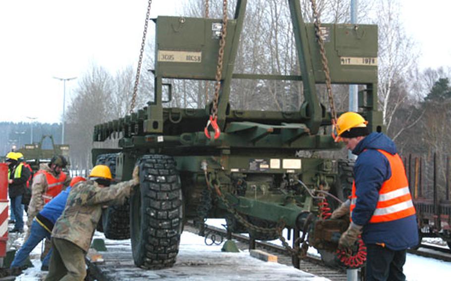 Workers at the Vilseck military railhead position the back chassis of a Palletized Load System truck on a rail car Wednesday as the specialized vehicles of the 41st Transportation Company were sent on the first leg of their journey to Iraq. The 41st soldiers will be reunited with their vehicles in Kuwait in March.