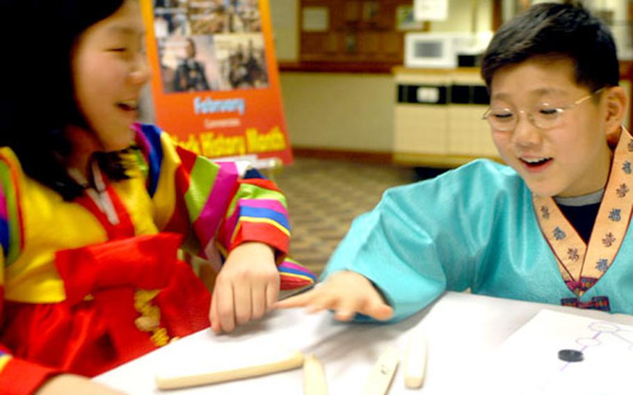 Su Hui Choe, 12, left, and Yon Sok Choe, 11, play a traditional South Korean game Wednesday at Camp Red Cloud, South Korea.