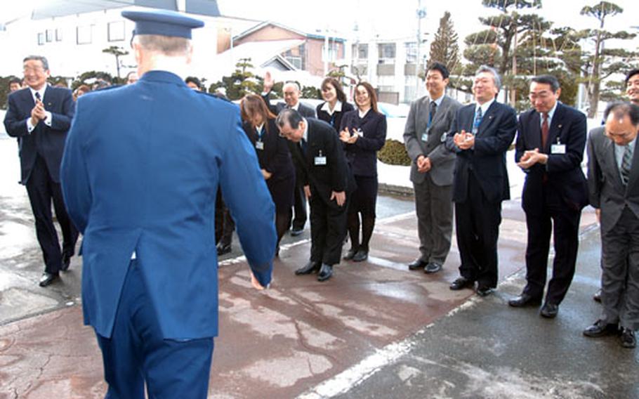 Misawa City Mayor Shigeyoshi Suzuki, far left, and his staff wave, bow and clap as U.S. Forces Japan Commander Lt. Gen Bruce A. Wright departs the mayor's office Monday.