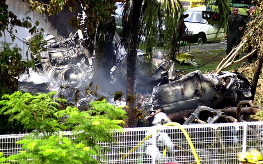 The wreckage of a Marine Corps CH-53D Sea Stallion smolders an hour after it crashed into a building at Okinawa Kokusai University on Aug. 13, 2004. Three crewmembers were injured in the accident, which occured close to Futenma Marine Corps Air Station.