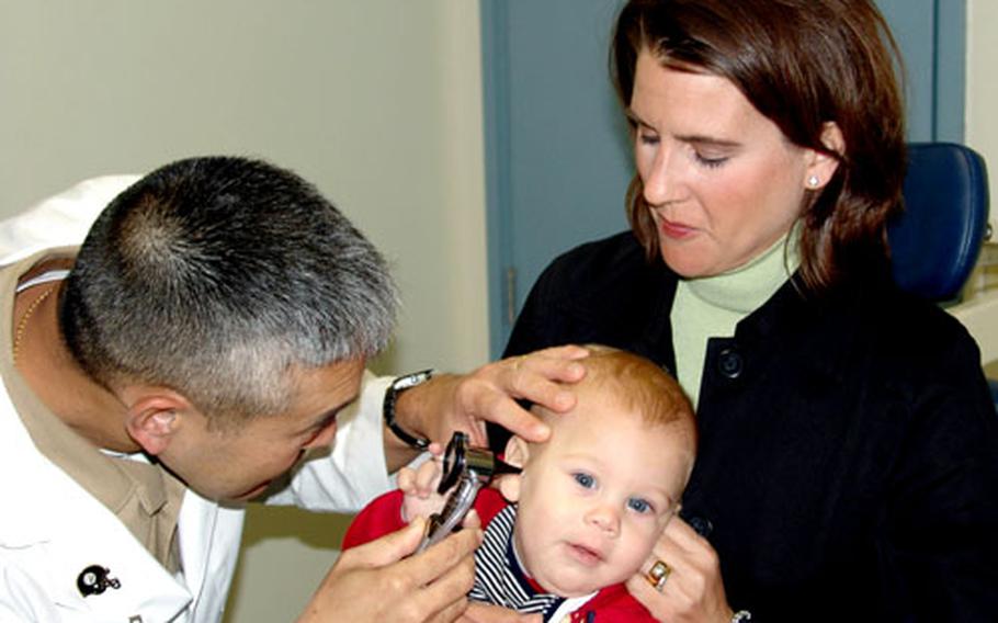 Lt. Cmdr. Mark Goto, otolaryngology department head at U.S. Naval Hospital Okinawa, checks the ears of Bennett Rad while mother Allison Rad holds him during a recent appointment at the hospital on Camp Lester, Okinawa.