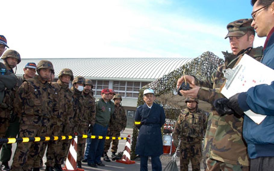 Holding a fake pipe bomb, Staff Sgt. Jonathan Homer, an Explosive Ordnance Disposal expert with 35th Civil Engineer Squadron, Misawa Air Base, Japan, talks to Japan Air Self-Defense Force 3rd Air Wing guard and transportation troops about the different kinds of Improvised Explosive Devices during an exercise on Tuesday.