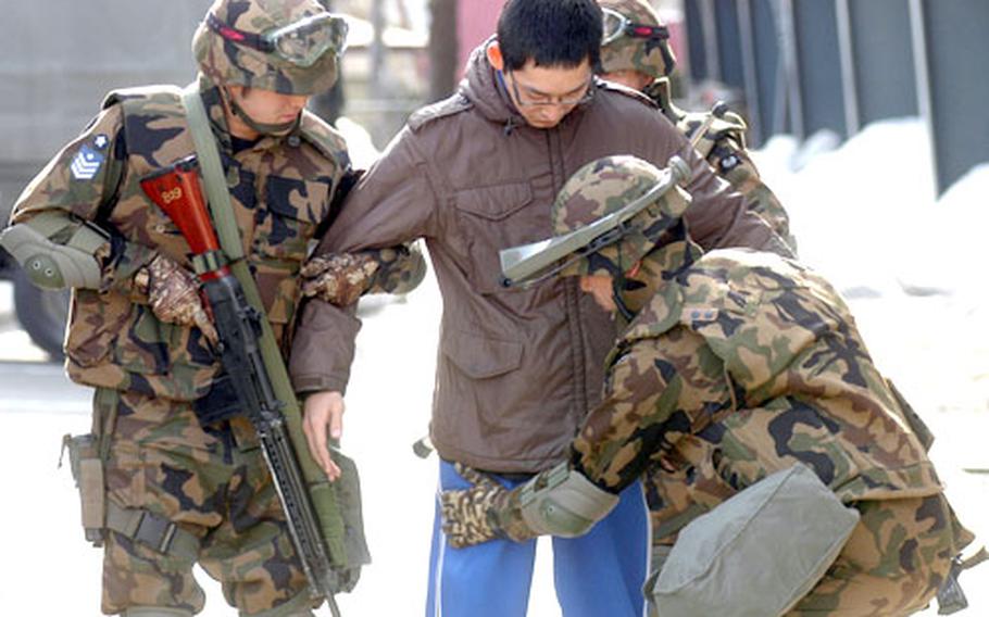 JASDF guard and transportation troops from 3rd Air Wing, Misawa Air Base, Japan, detain a driver after finding an Improvised Explosive Device prop in his vehicle during the exercise.