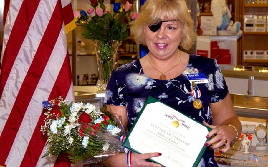 Sarah Latona, an Army and Air Force Exchange Service employee injured while working in Iraq, poses during a ceremony in Mountain Home, Idaho, after receiving the Defense of Freedom Medal, the civilian equivalent of the Purple Heart.