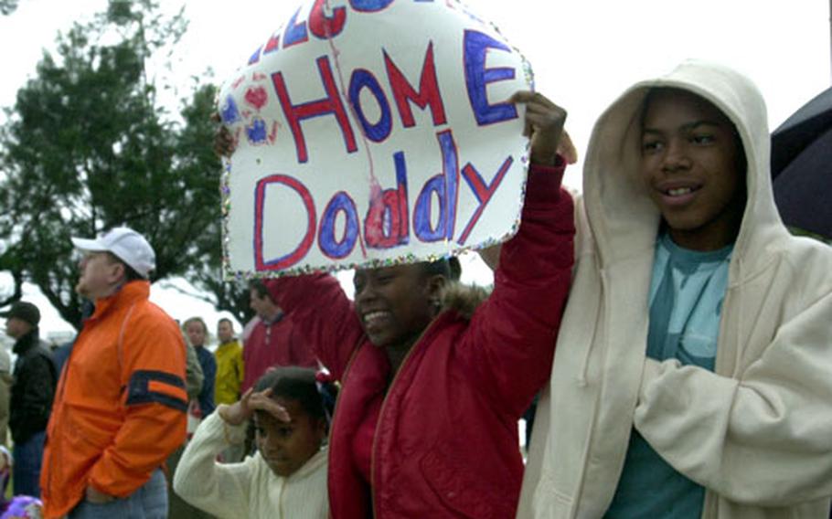 Toshia White, center, flanked by sister Taosha and brother Eric, holds up a sign Saturday at White Beach Naval Facility, Okinawa, welcoming their father, Sgt. Darrell Aming, back from Iraq. More than 2,000 Marines and sailors assigned to the 31st Marine Expeditionary Unit arrived back home after an eight-month deployment.