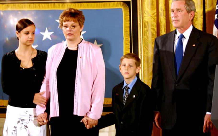 Joining President Bush on the podium as Sgt. 1st Class Paul Ray Smith's Medal of Honor citation is read are Smith's widow, Birgit, and children Jessica and David.